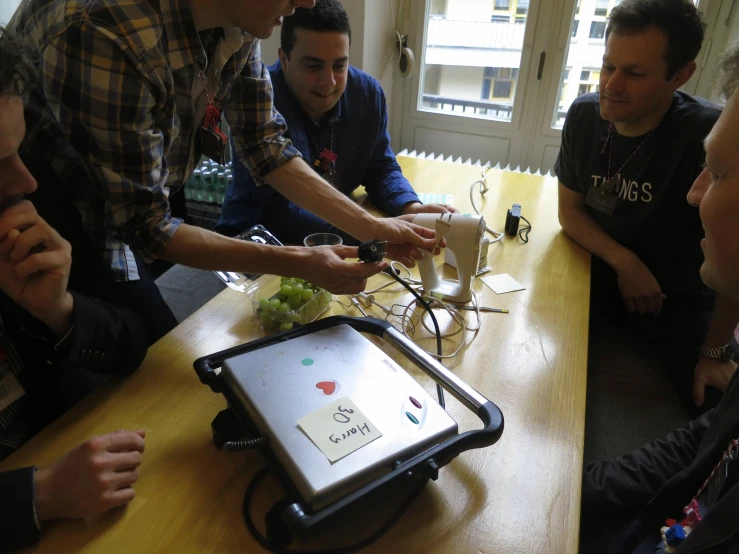 a group of guys looking at soing on a small screen