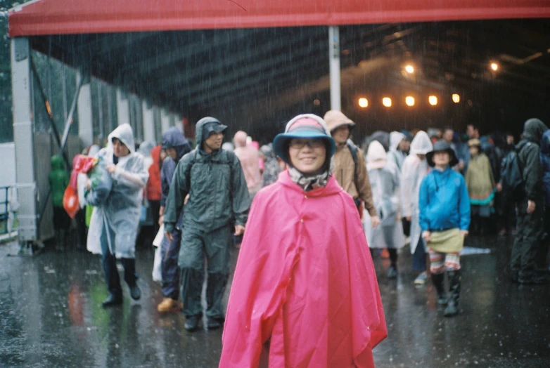 a small boy wearing a red raincoat and standing outside