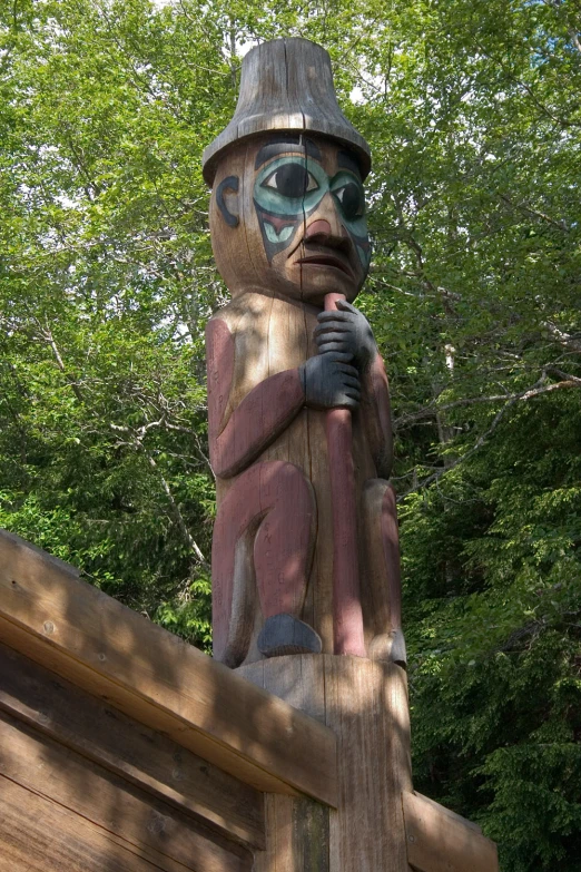 a wooden carved statue sitting on top of a lush green forest