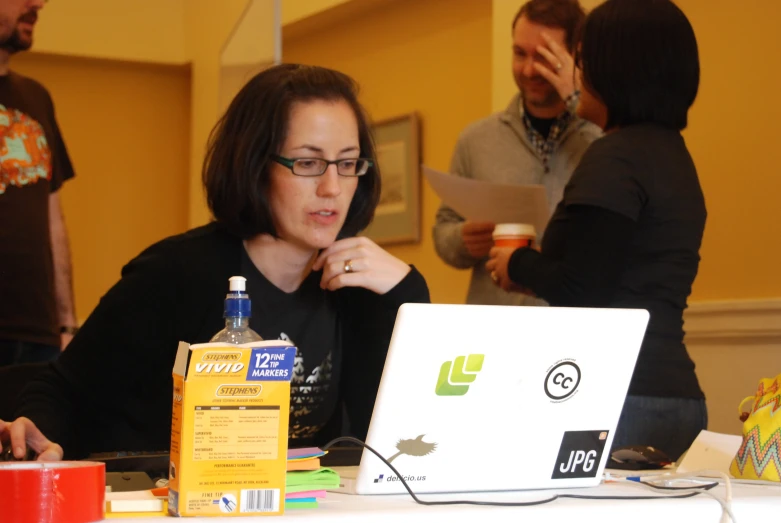 a girl is looking at a bottle near a laptop