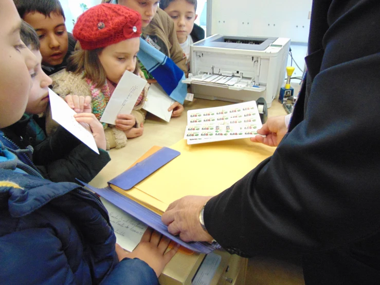 young students learning letters from a small paper