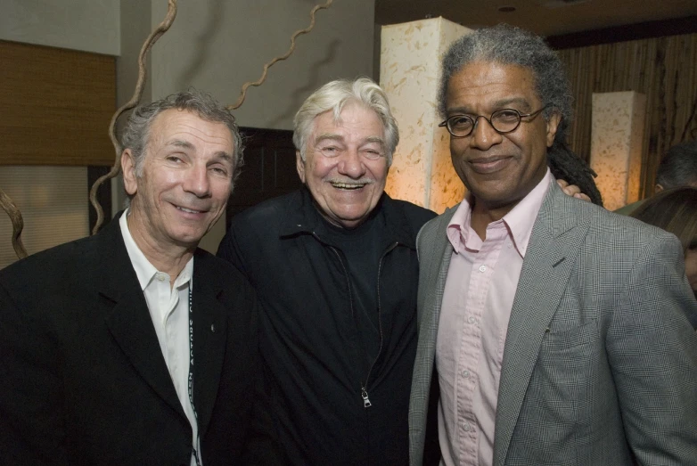 a man smiling next to two older men