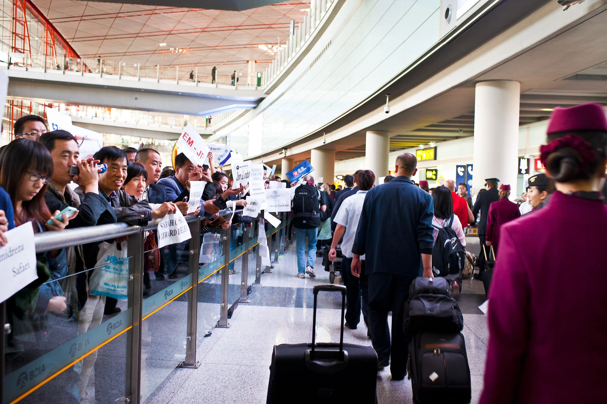 people with suitcases walking down the mall walkway