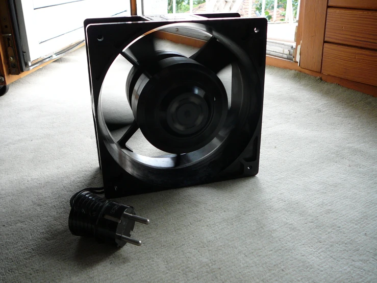 a fan sits in a room near a remote