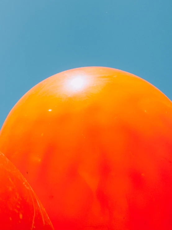 two large orange balloons with blue skies in the background