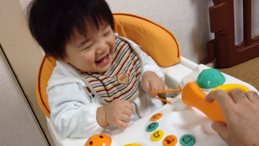 a small baby is laughing while sitting in a toy chair