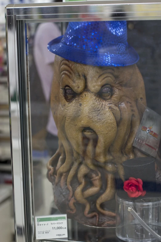 a strange looking mask wearing blue hat on display