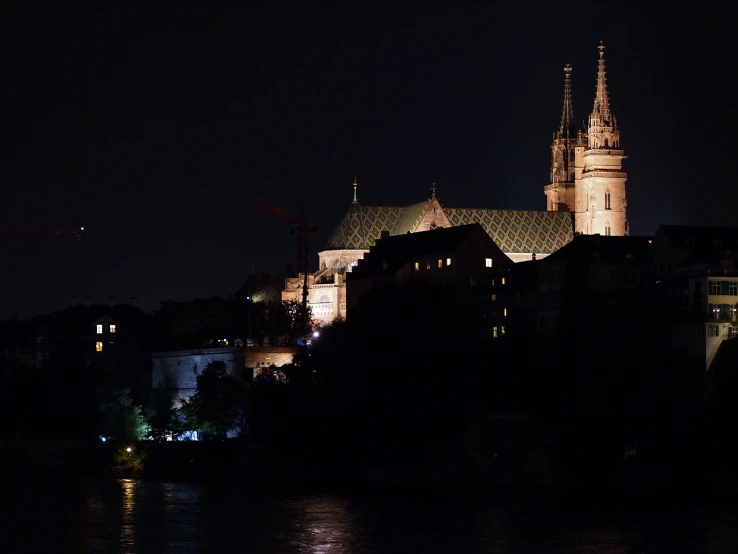 a castle sits at night overlooking a body of water