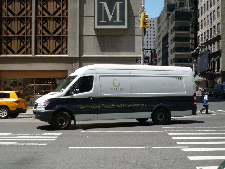 a van with the m on it is driving through a city intersection