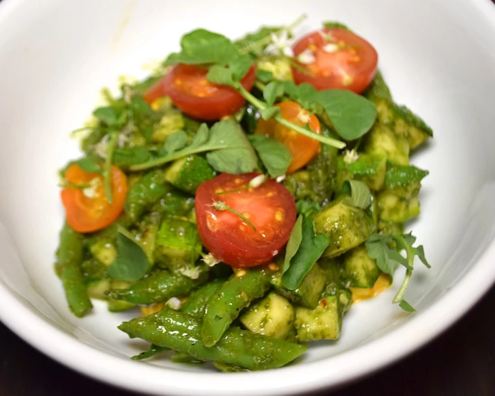 green vegetables with tomatoes on top are in a bowl