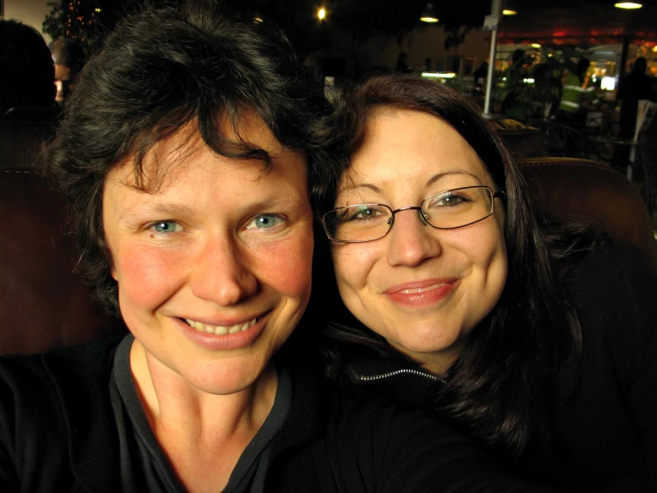 two women are posing together in front of a building