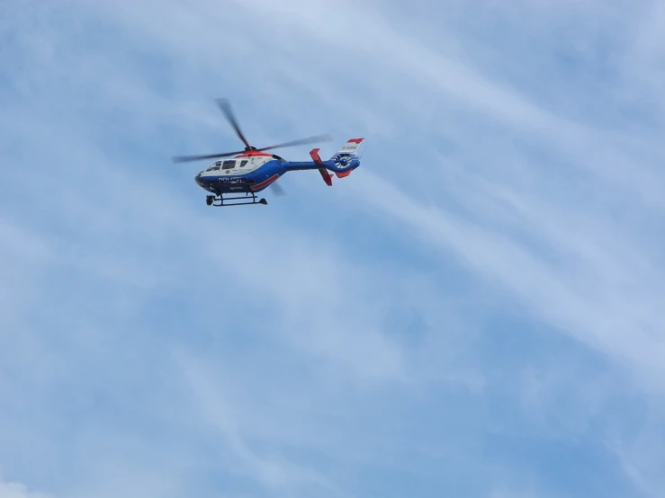 a helicopter flying through the blue sky, looking for landing