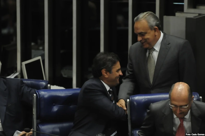 two men in suits greet each other in the middle of the assembly