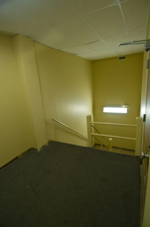 an empty room with a doorway, stair and some light