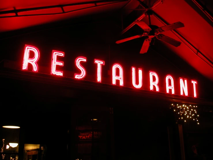 a sign is lit up at night that says restaurant