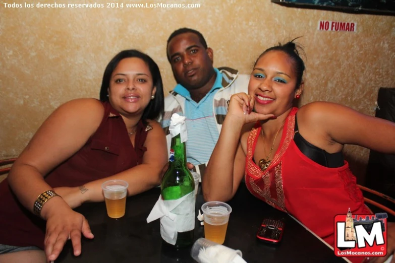 three people smiling at a table with drinks