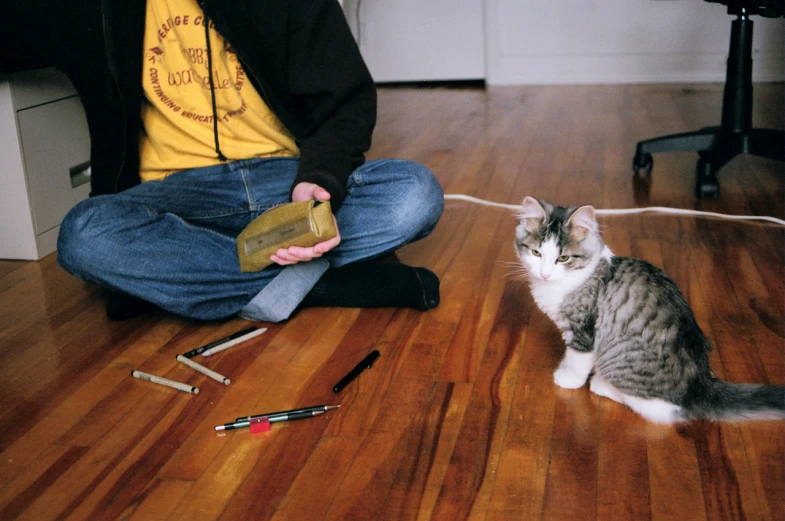 a cat sitting on the floor by someone with scissors