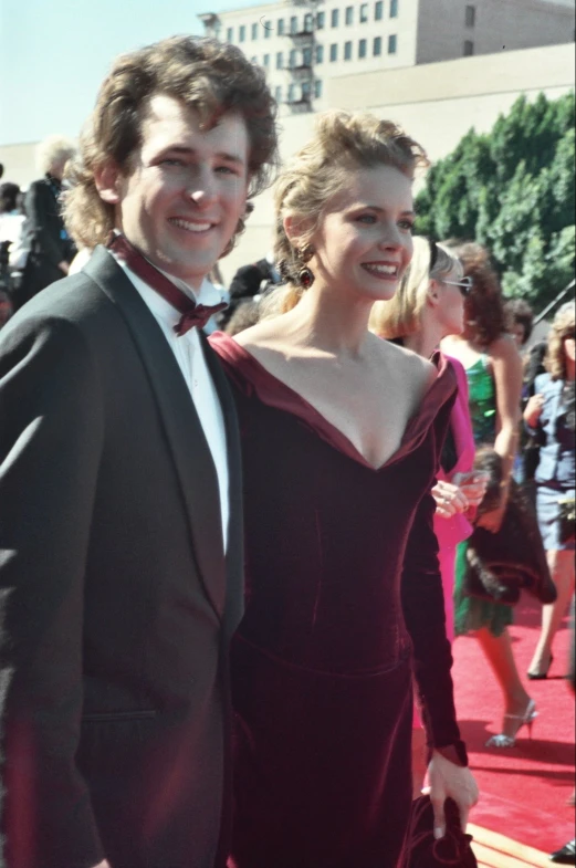 a young couple wearing formal wear standing on the red carpet