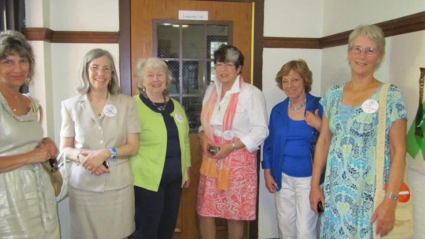 several women are standing by a door, one wearing a green jacket