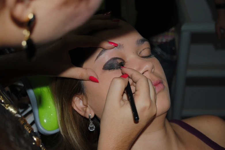 a young lady putting on makeup for another woman