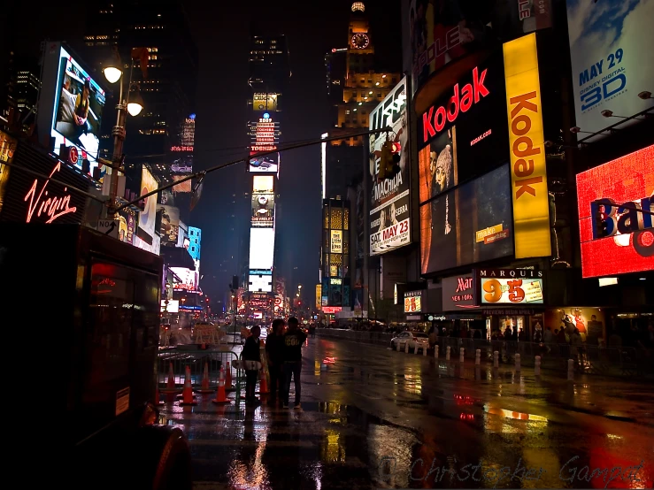 people walking on a wet street in the city at night