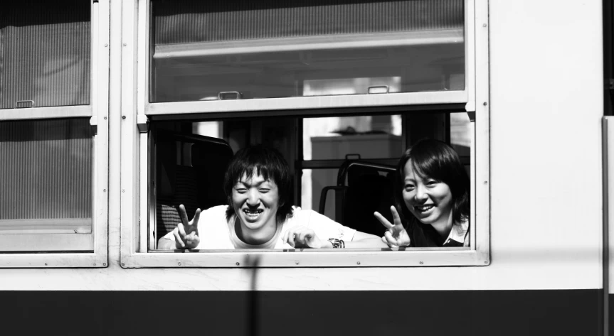 two people sticking out their fingers in front of a window