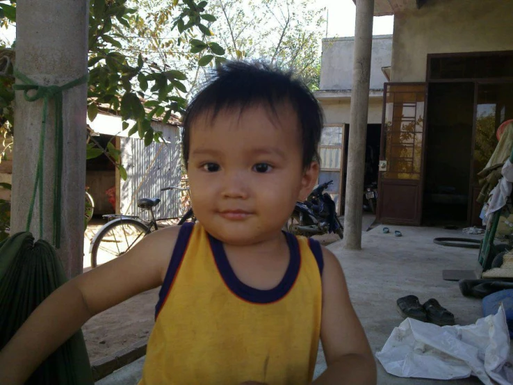 a small child with dark hair and yellow shirt on