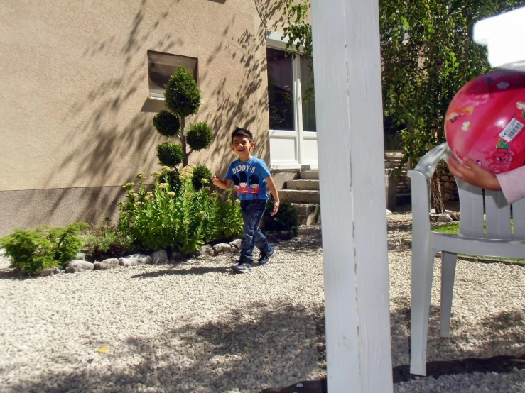 a child walks past a fake air plant in front of a house