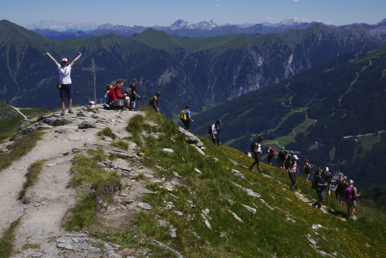 a man with a white shirt on standing at the top of a mountain