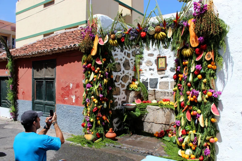 a person taking a po of a colorful fruit decoration on the side of a building
