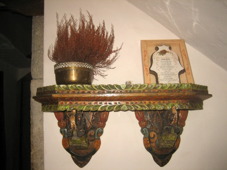 a vase with flowers on top of a mantle