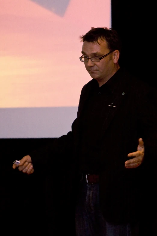 a man speaking in front of a projector screen