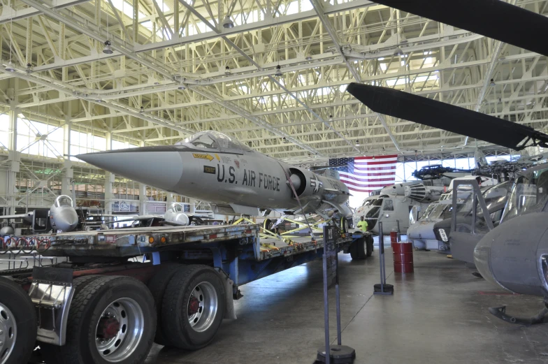 a large airplane sits on a large flat bed in the garage