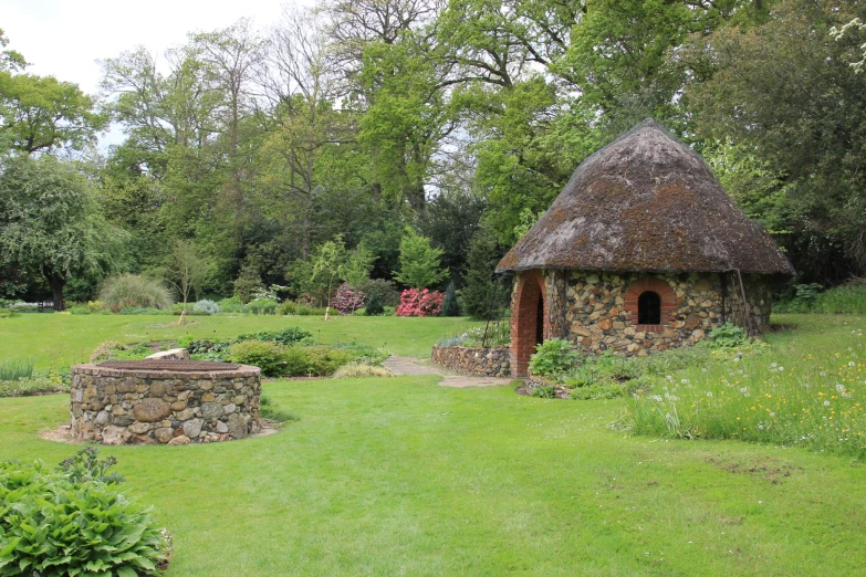 an old thatched building with two circular arches sitting in a garden