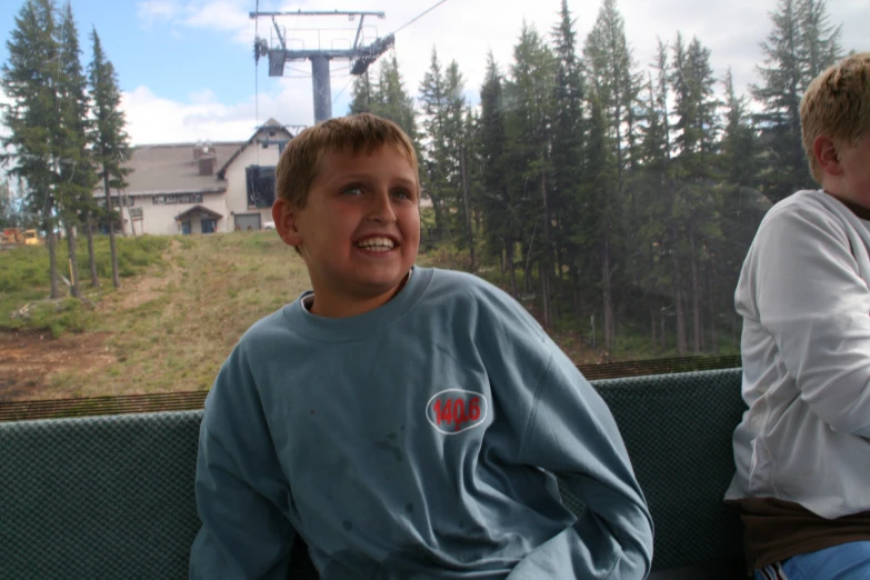 two s who are smiling while riding on a cable car