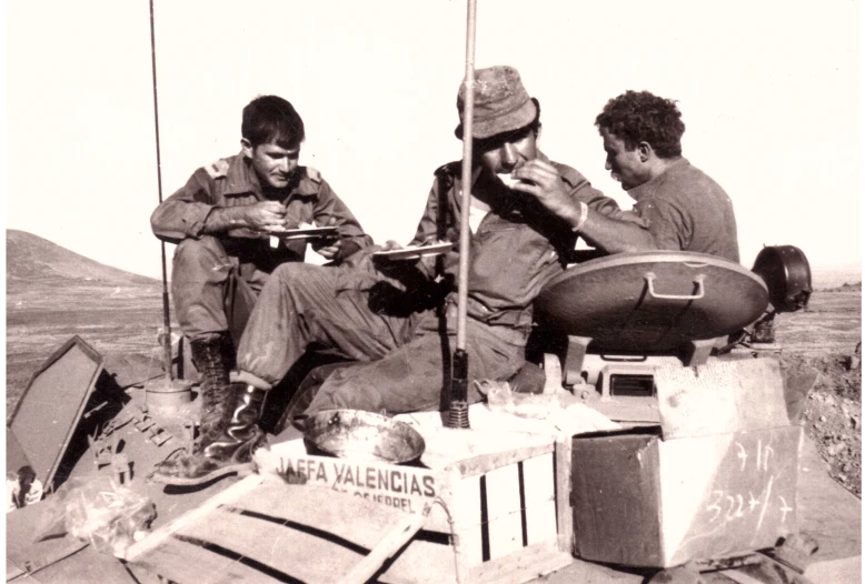 two men sitting next to each other while one eats