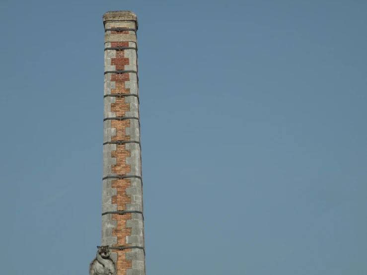 a tall brick tower next to a small bird statue