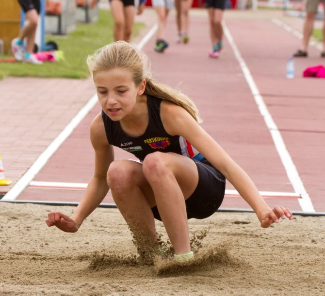 little girl playing in the sand at a track