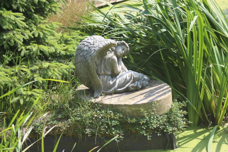 a stone statue sitting on a rock in a garden