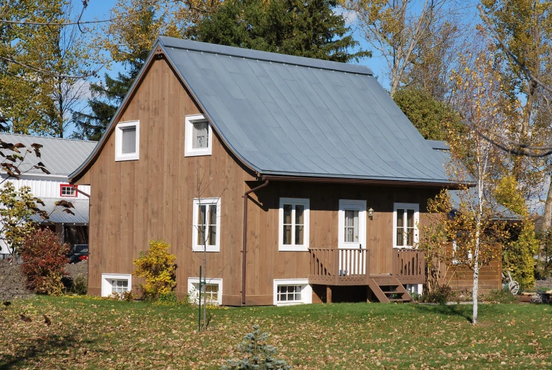 a brown cabin sitting in the grass next to a building