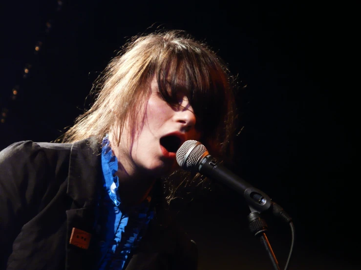 a woman with blond hair singing into a microphone