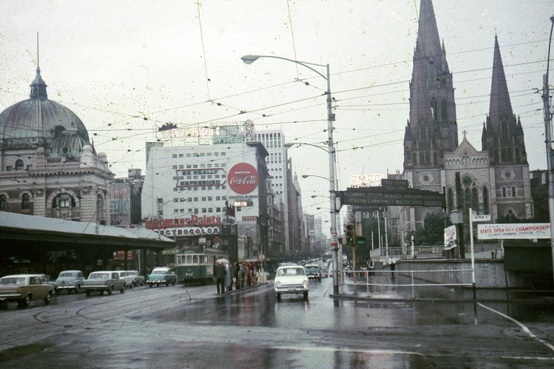 a city street in the rain with cars driving down it