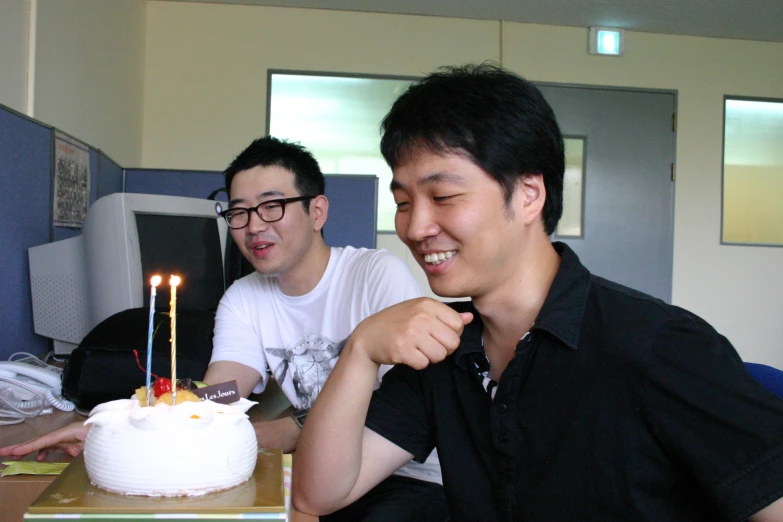 two young men celeting one of their birthdays with candles