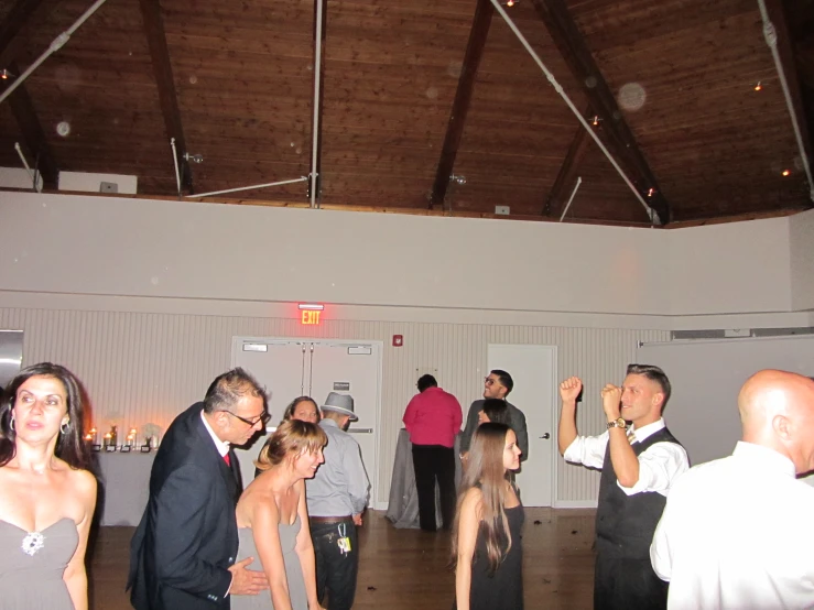 several people are dancing at a party with a man in a suit and tie