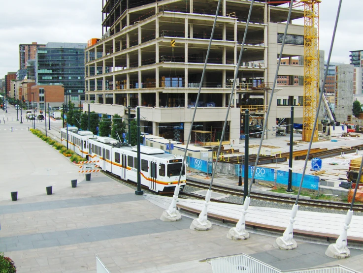 this is a cable car on tracks in front of a building under construction