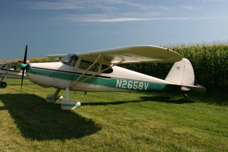 small aircraft on grassy field with fence in background