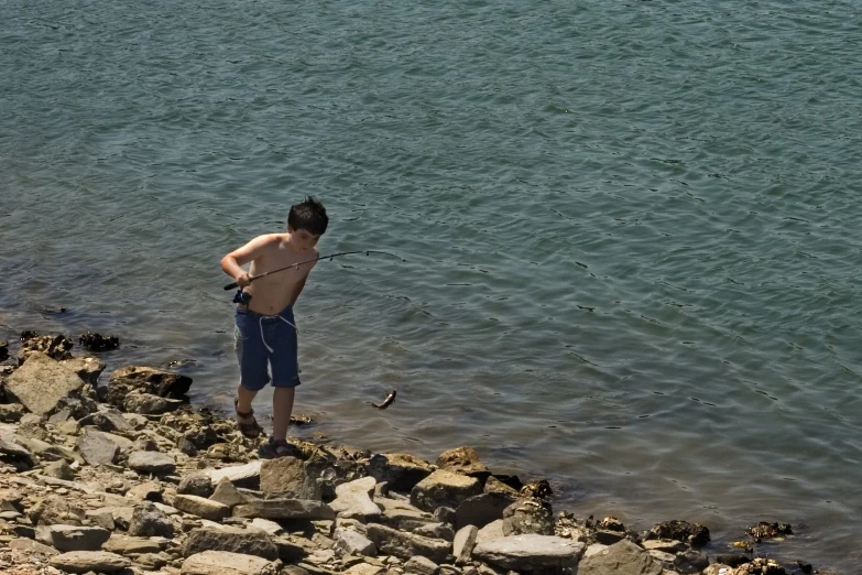 a  is fishing off the edge of a rock cliff