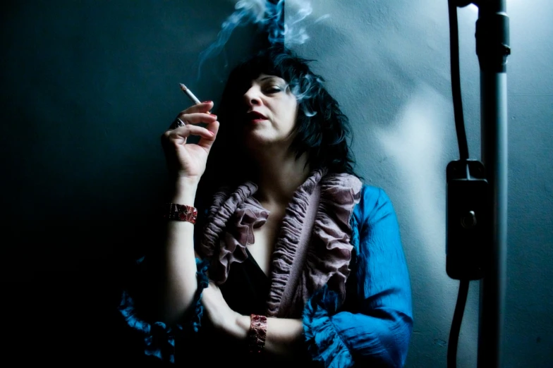 a woman in blue dress smoking a cigarette