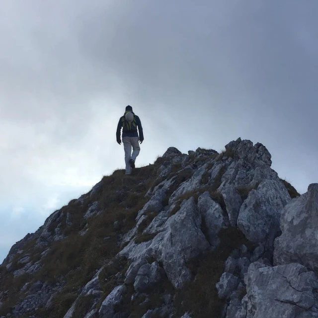 person walking up the steep grassy hill on top of a mountain