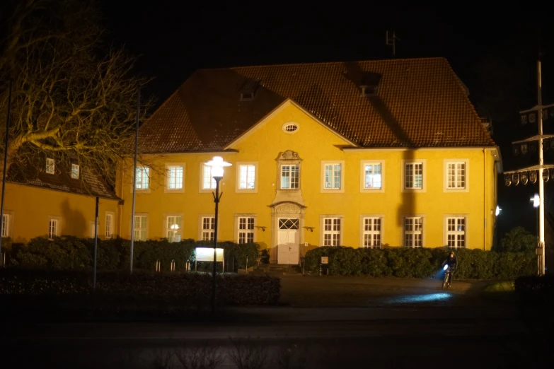 a large yellow house with some trees and lights in the front yard